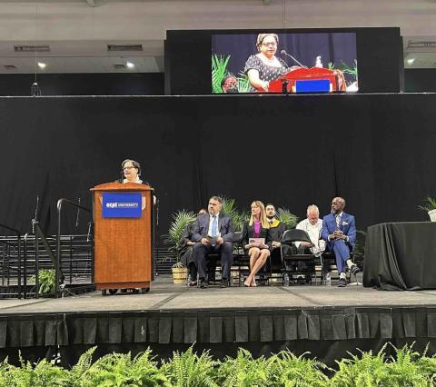 Rep. McClellan stands on stage behind a podium to deliver commencement speech
