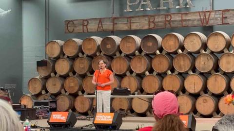Rep. McClellan stands on stage at the Mom's Demand Action Wear Orange Event