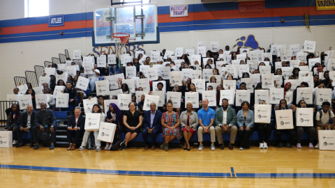 Photo of Rep. McClellan sitting with the senior class of Armstrong High School holding laptops.